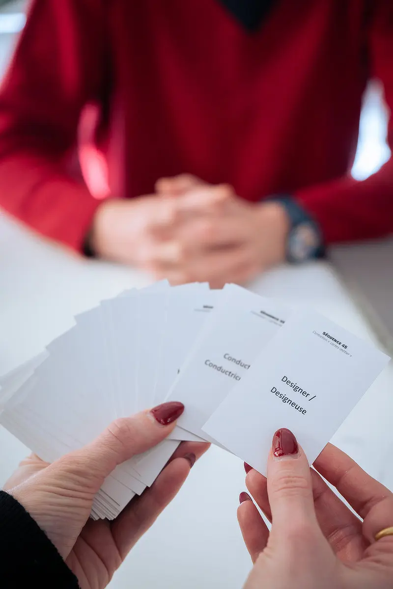 Cartes de métiers dans les mains d'une cliente lors d'un entretien de bilan de compétences.